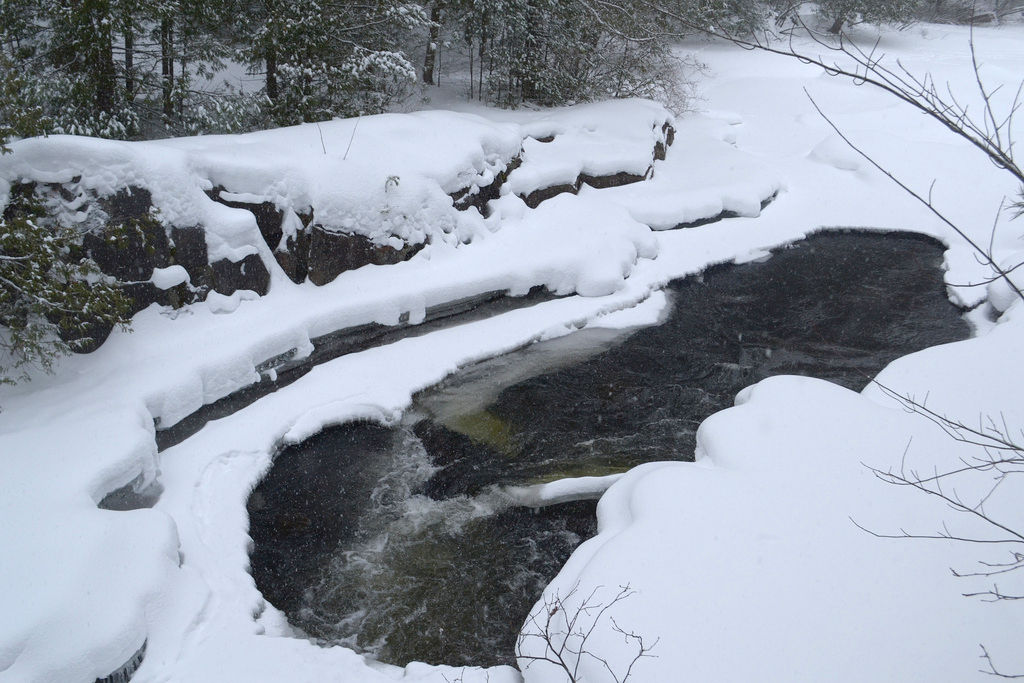A stream runs under heavy snow in Daves Falls county park