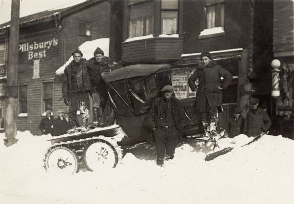 Men pose with early snowmobile