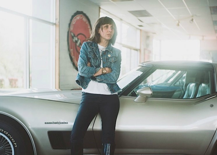 Jessica Hopper stands in front of a vintage car, arms folded across her chest