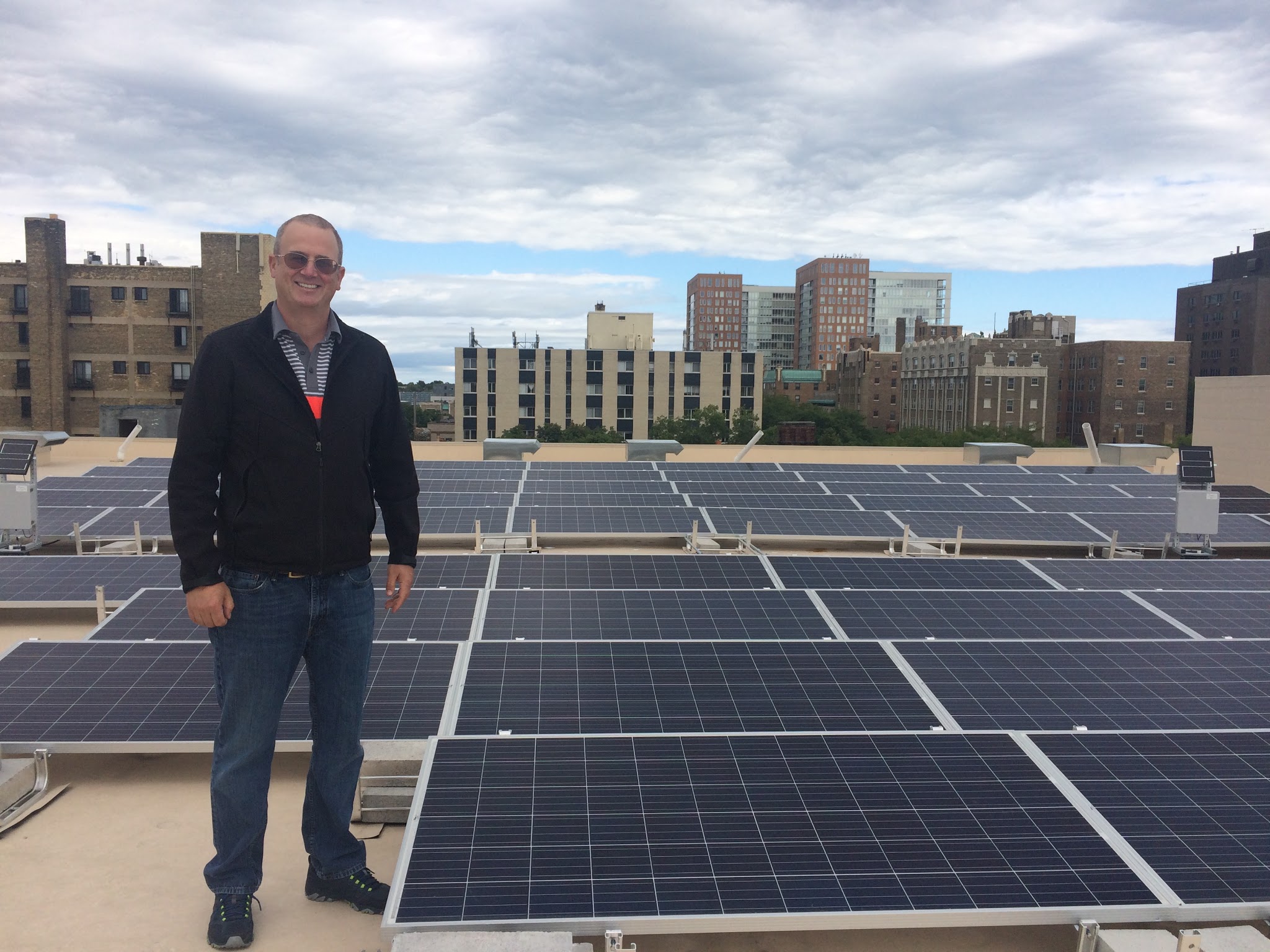 Mike O'Connor stands next to solar panels
