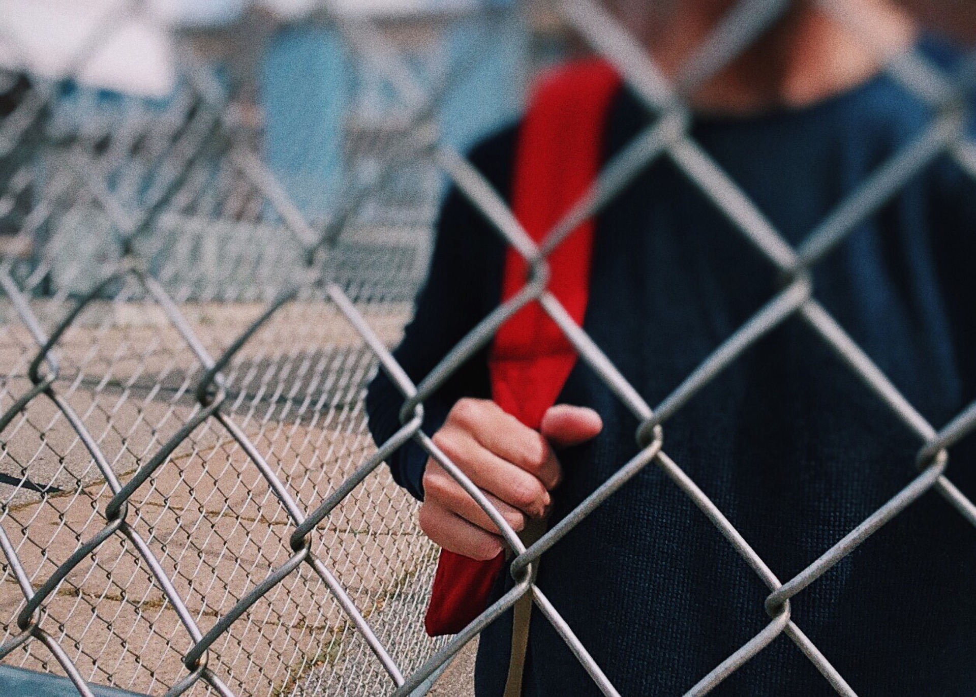 kid with backback behind fence