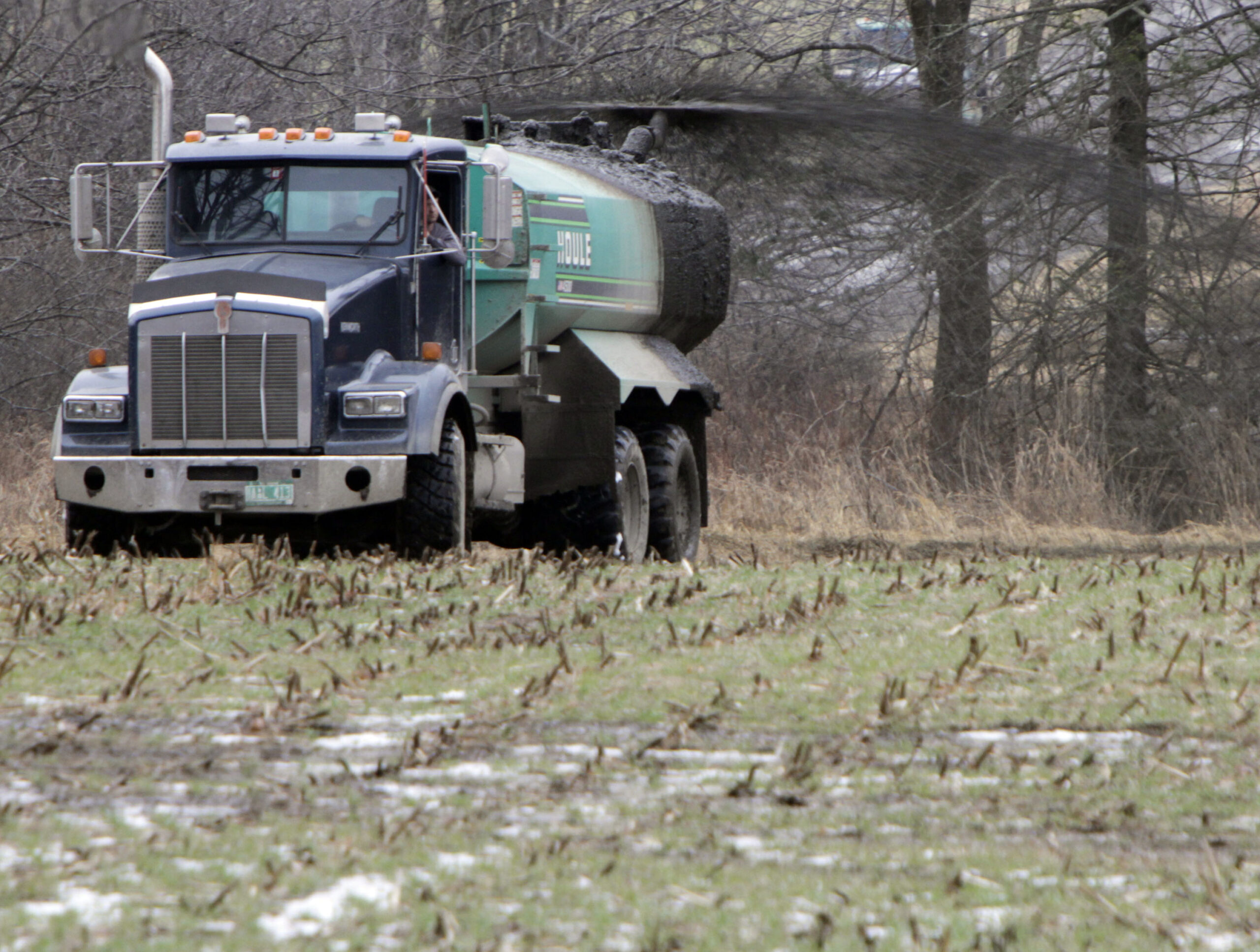 truck spreads manure on a farm field
