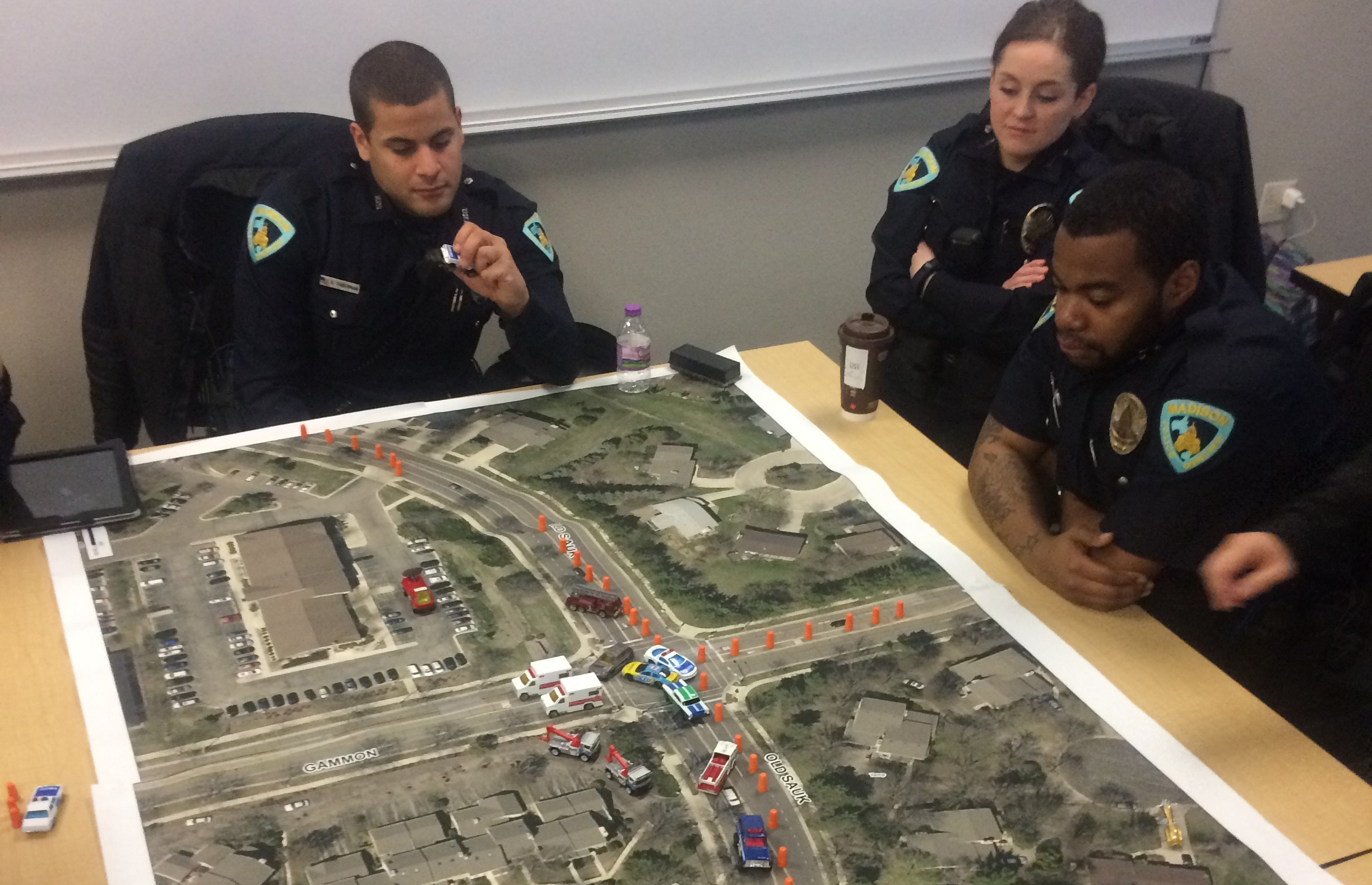 Madison Police recruits learn to stage emergency vehicles at the site of a traffic crash using a map of Madison and matchbox cars.
