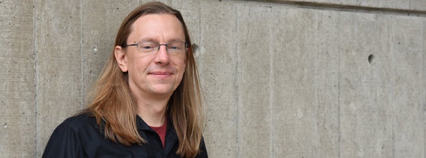 Rob Ferrett standing against a raw concrete wall