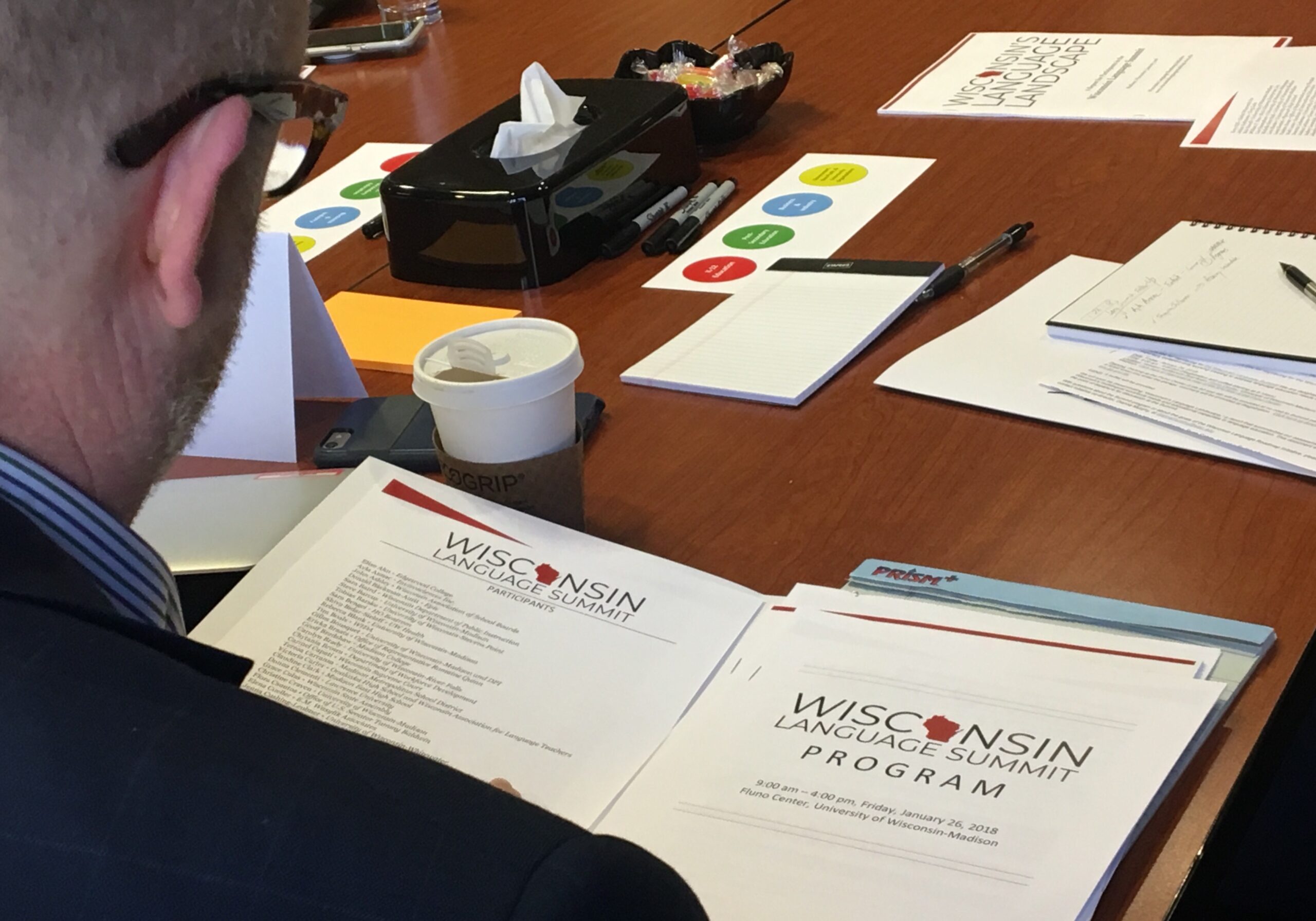 Man looks at folder with documents titled Wisconsin Language Summit Program