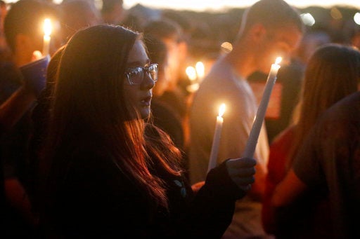 Attendees raise their candles at a candlelight vigil