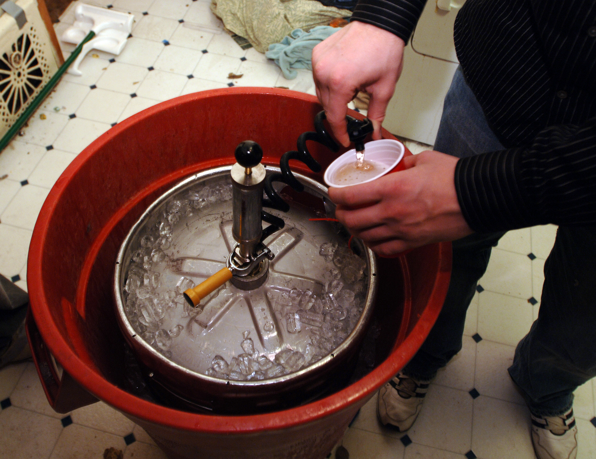 A plastic cup is filled with beer from a keg