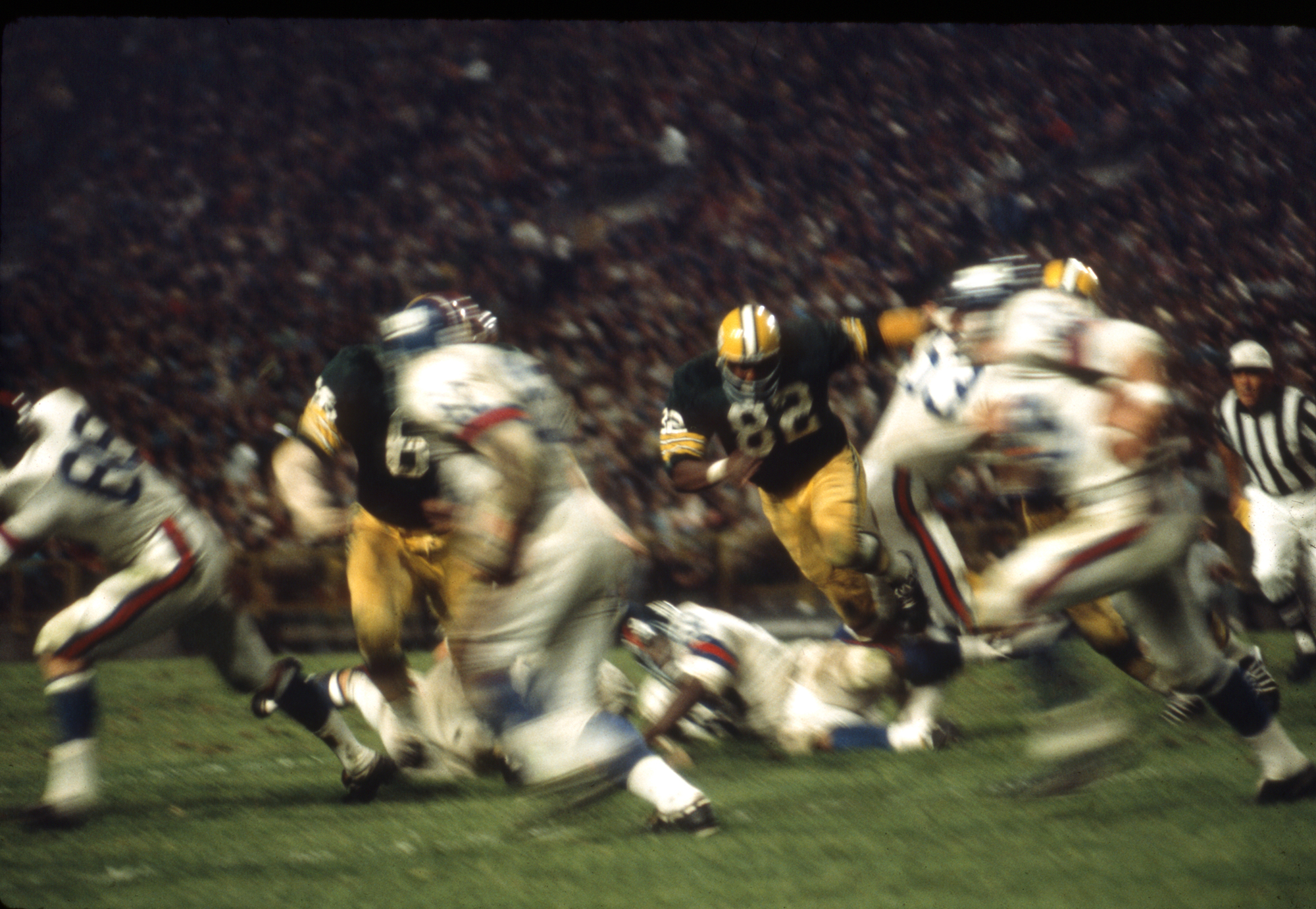 In a blur of excitement Lionel Aldridge (82) and Ray Nitschke (66) push through the Giants offense
