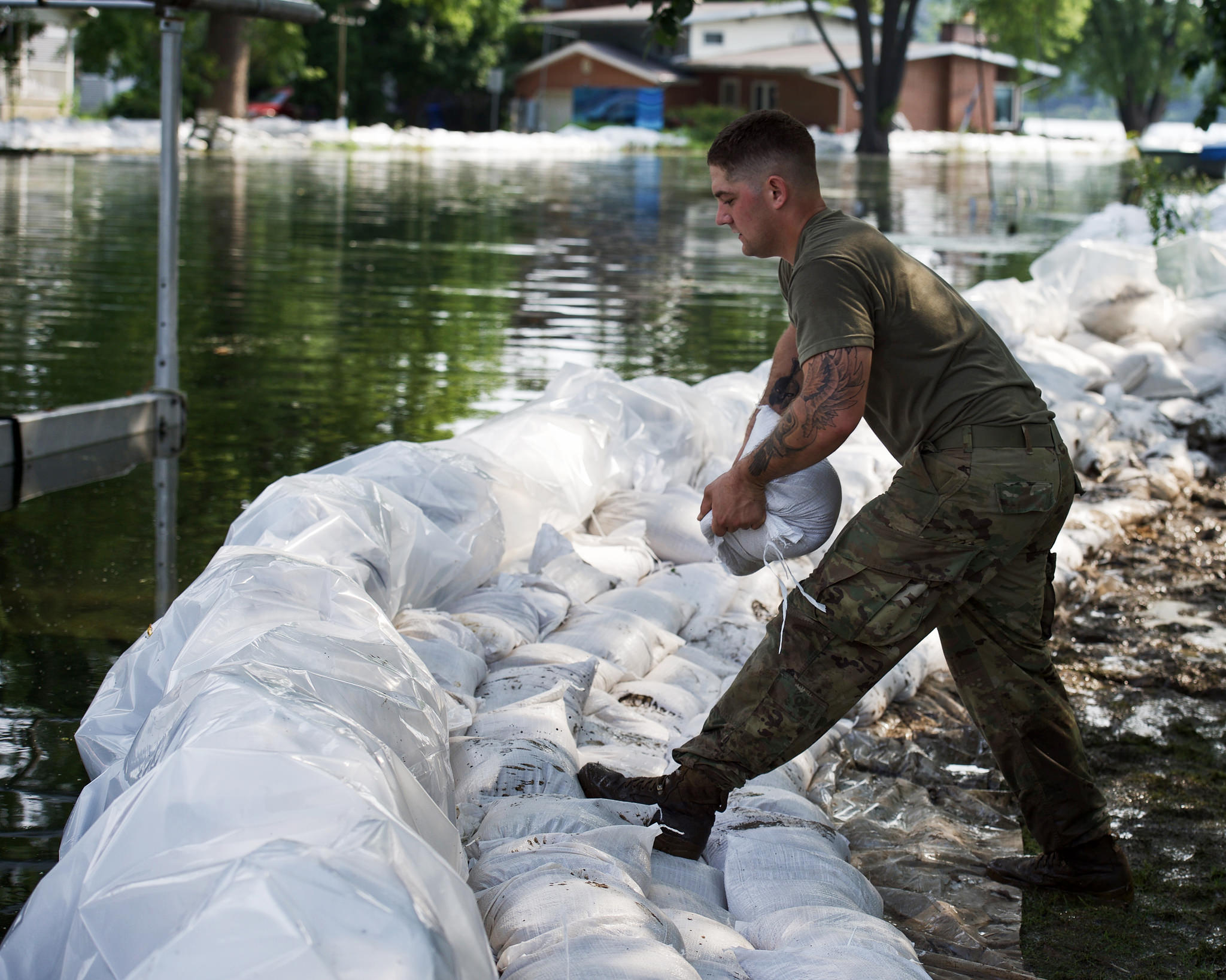 A soldiers assists local citizens in sandbagging efforts after flooding