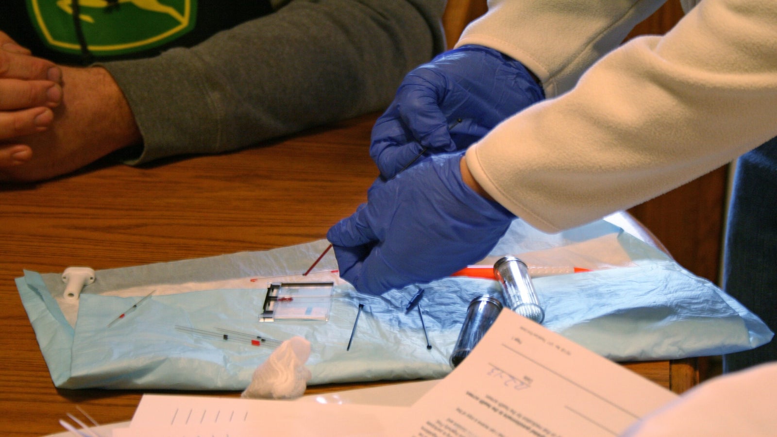 Nurse Dawn Dingeldein places blood drawn from farmer Jay Vomastic on a slide