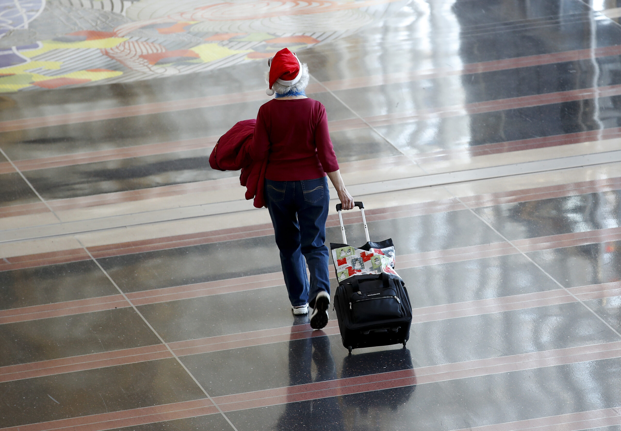 woman A woman in a Santa hat rolls her luggage through airport