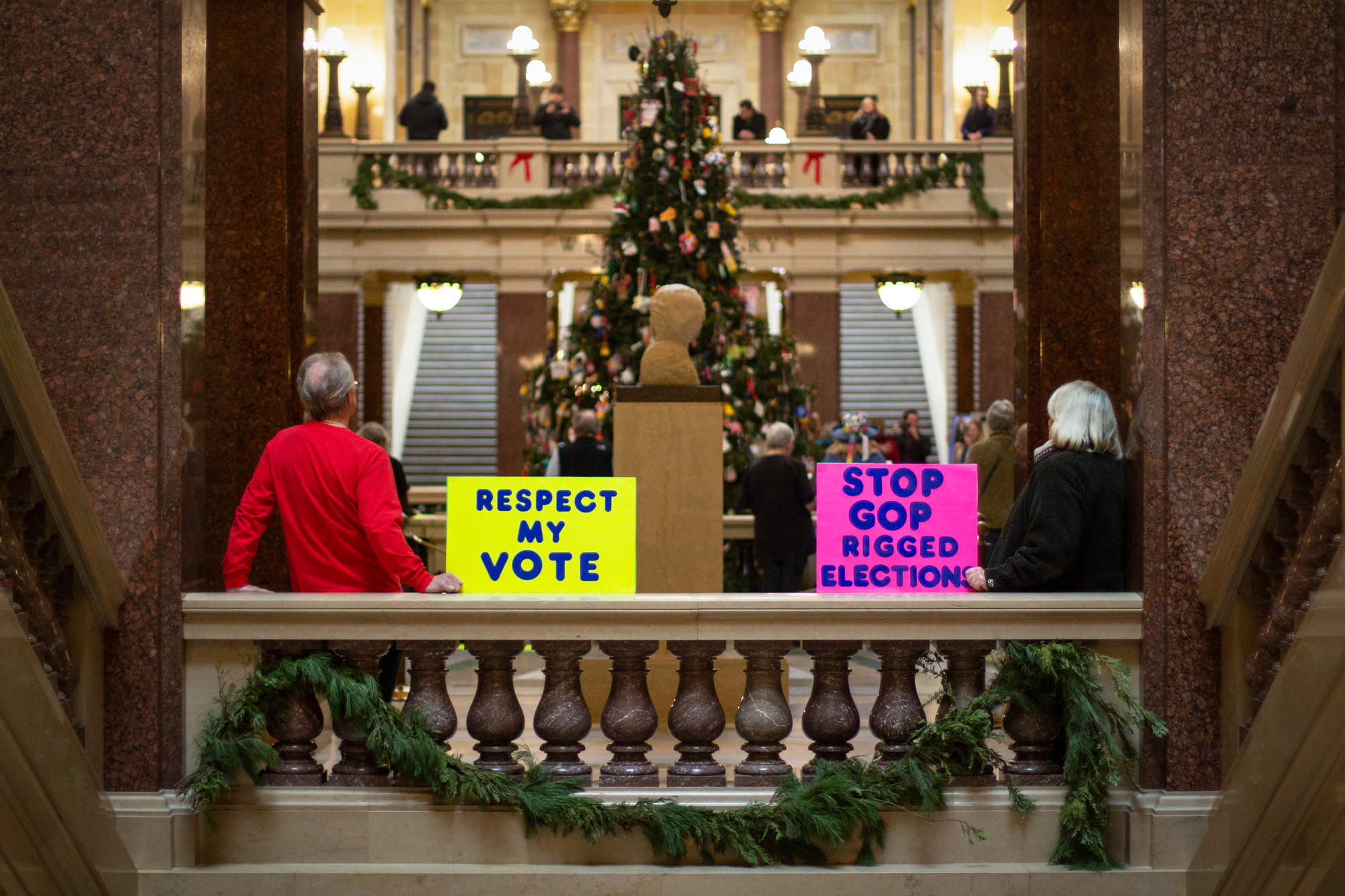 Public citizens hold up signs inside the Capitol calling for Republican lawmakers to respect their votes