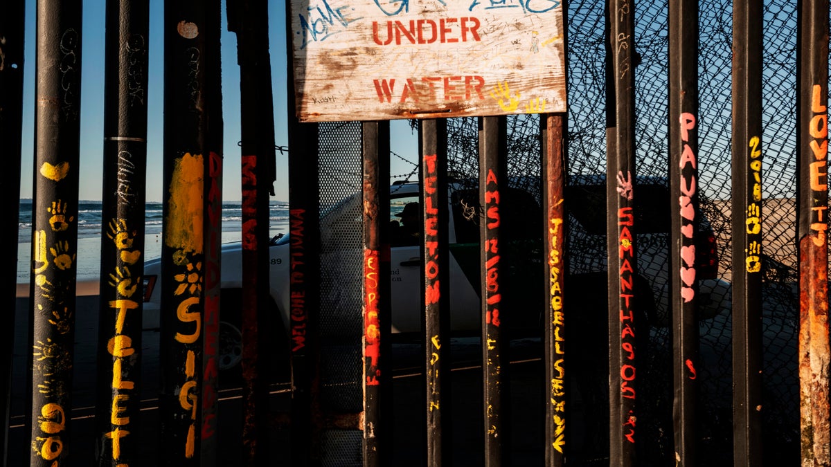 a border patrol office inside his vehicle guards the border fence at the U.S. side of San Diego, Calif., as seen from Tijuana, Mexico.
