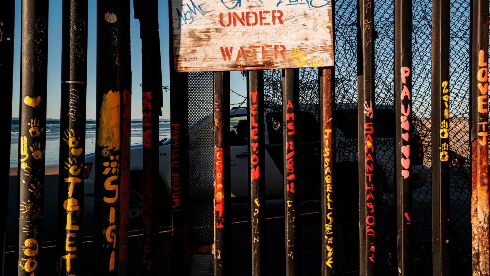 a border patrol office inside his vehicle guards the border fence at the U.S. side of San Diego, Calif., as seen from Tijuana, Mexico.