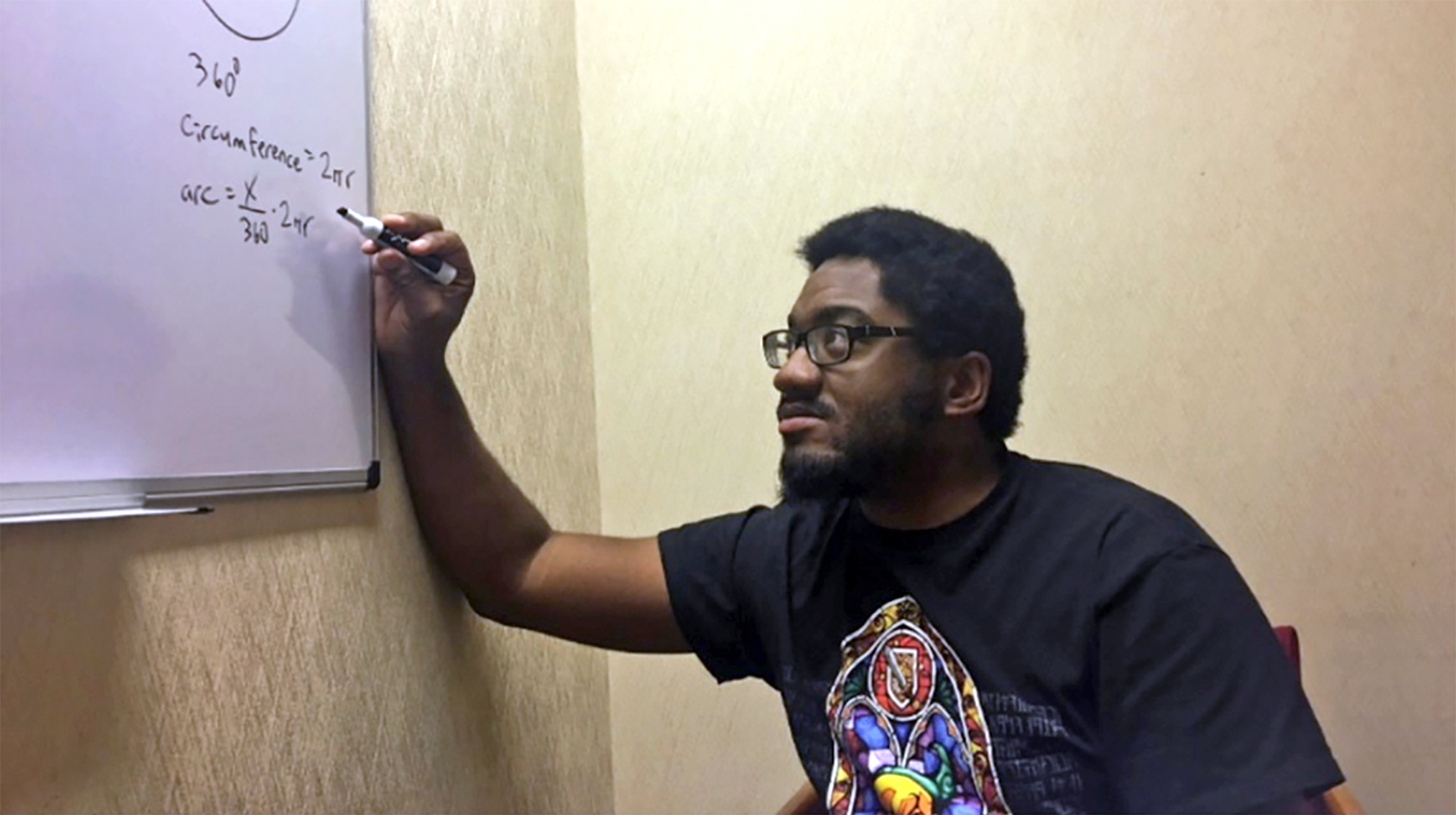 Shareef Jackson writes on a dry-erase board in a classroom