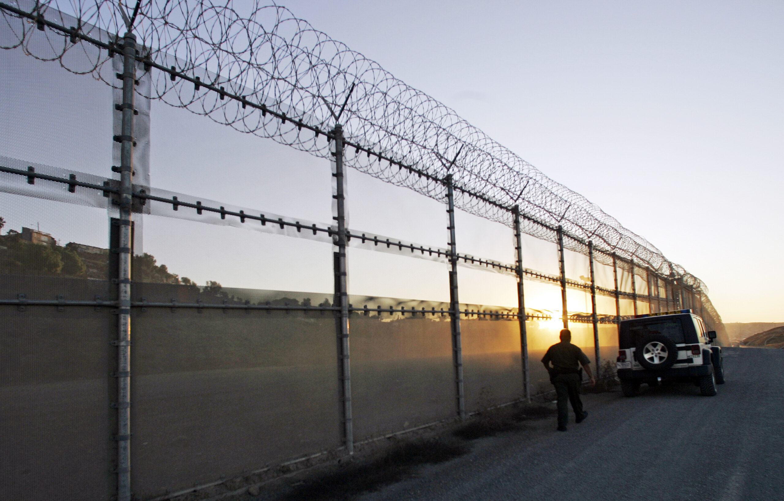 U.S. Border Patrol agent walking back to his vehicle along the border fence in San Diego, California.