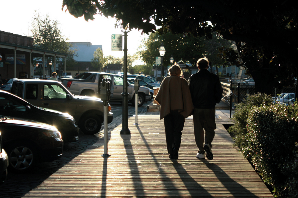 an elderly couple walking side by side on a boardwalk