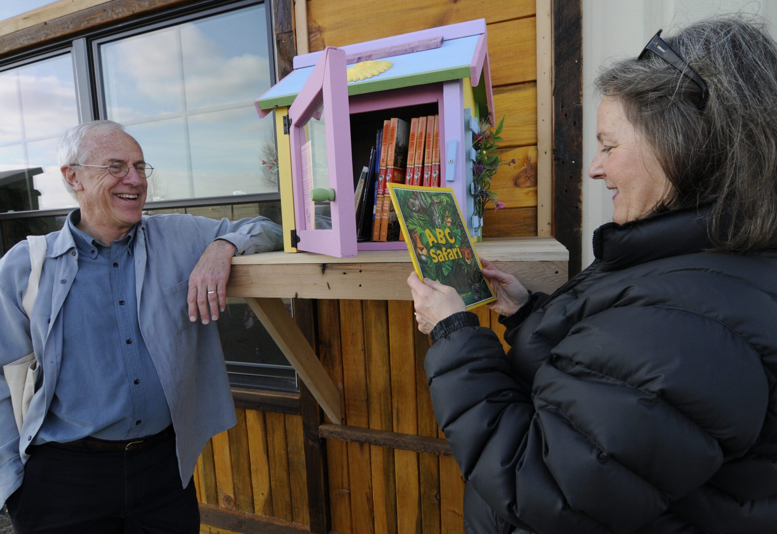 Two people making selections from a little free library