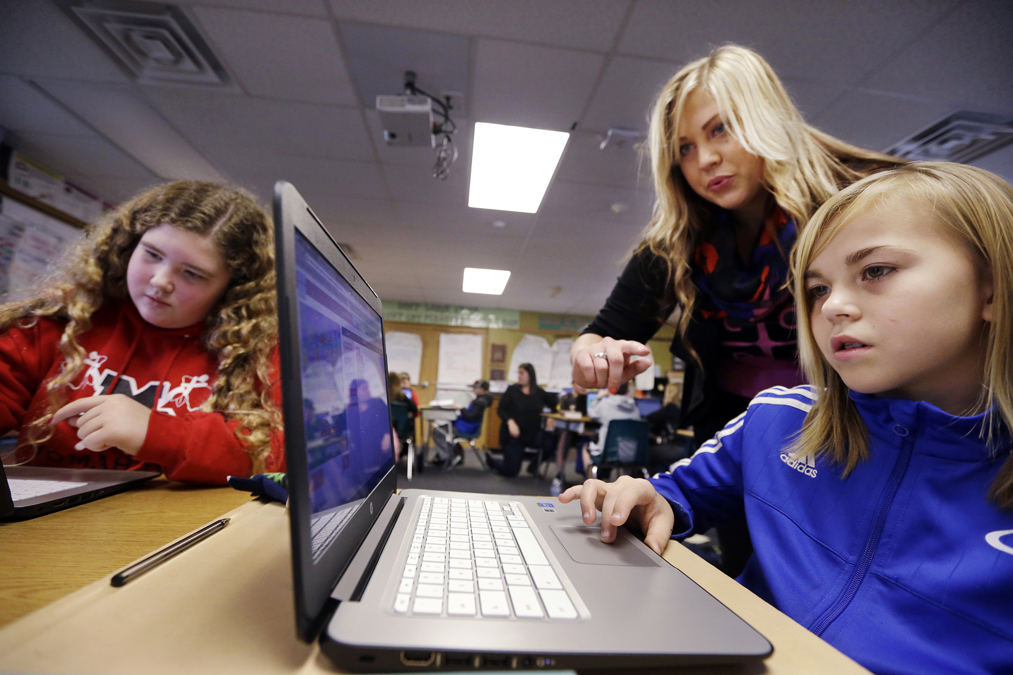computer science teacher helps fifth grade students work on programming
