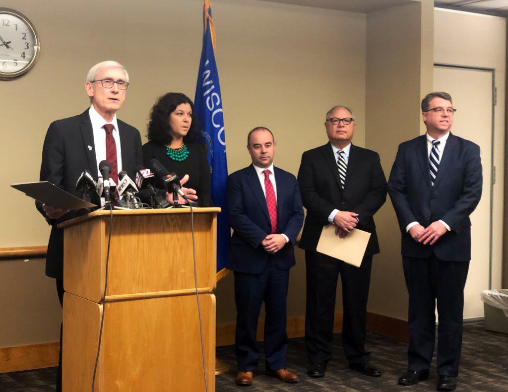 Governor Evers in front of a podium with cabinet officials