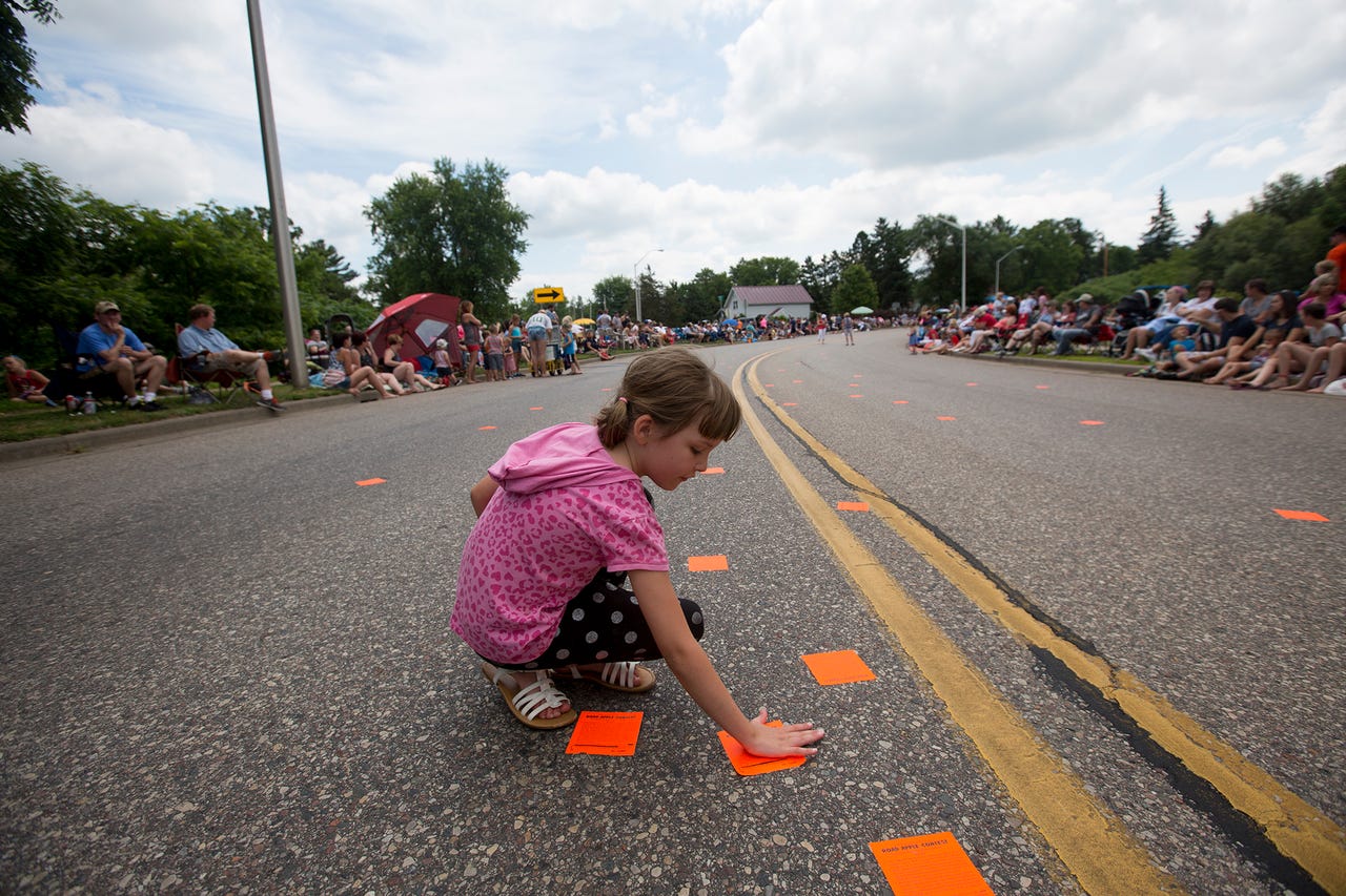 young girl placing road apple contest sticker on pittsville fourth of july parade route