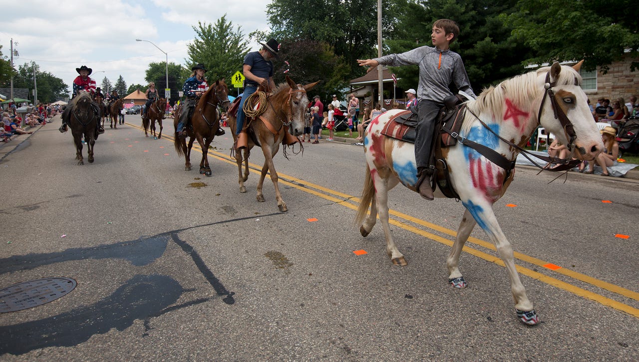 A youngster throws candy to the crowd from his horse during the Fourth of July parade in Pittsville