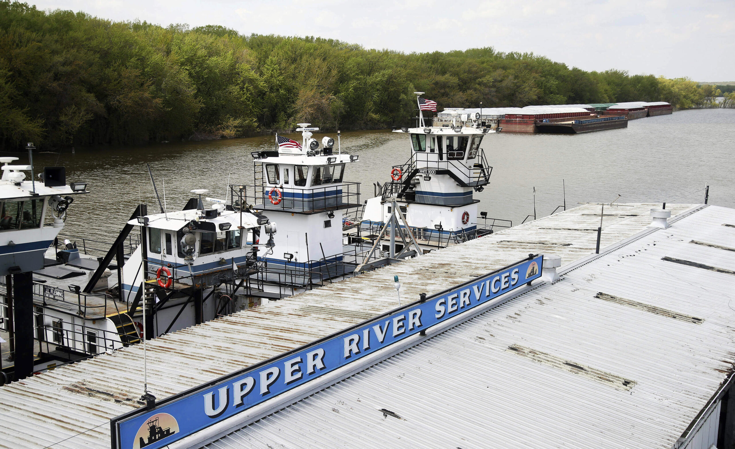 In this Tuesday, May 14, 2019 photo, empty barges, background right, are moored at the Upper River Services along with tug boats on the Mississippi River in St. Paul, Minn., as spring flooding interrupts shipments on the river. Historic Midwest flooding t