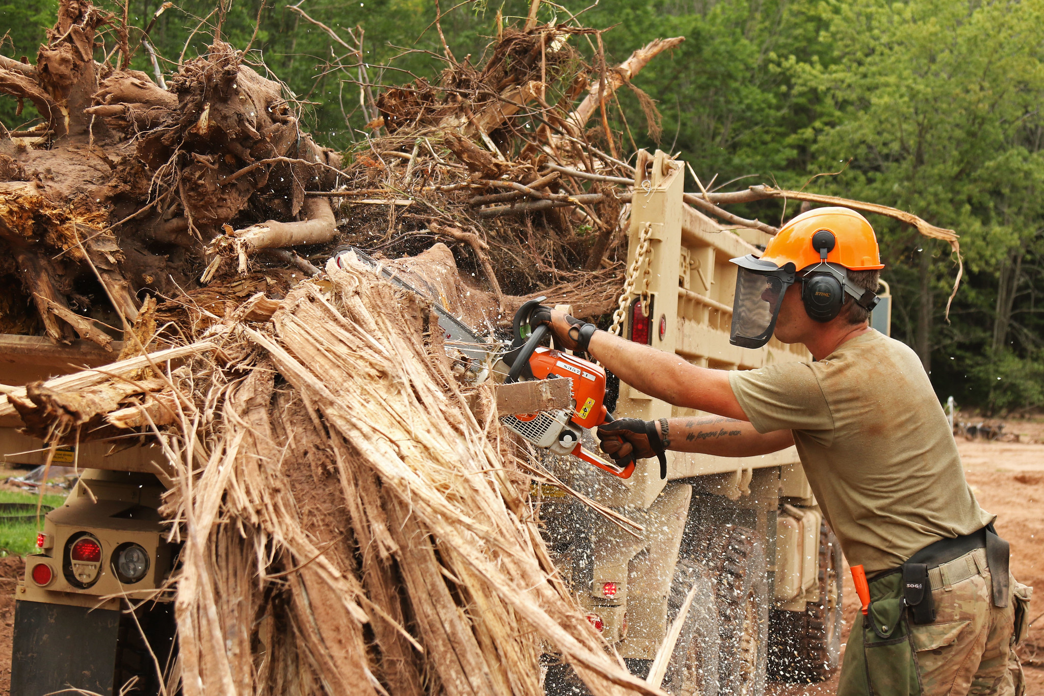 Spc. Justin Meagher operates a chain saw to cut up large debris