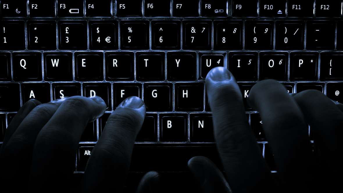 Close-up of person typing on lit-up keyboard