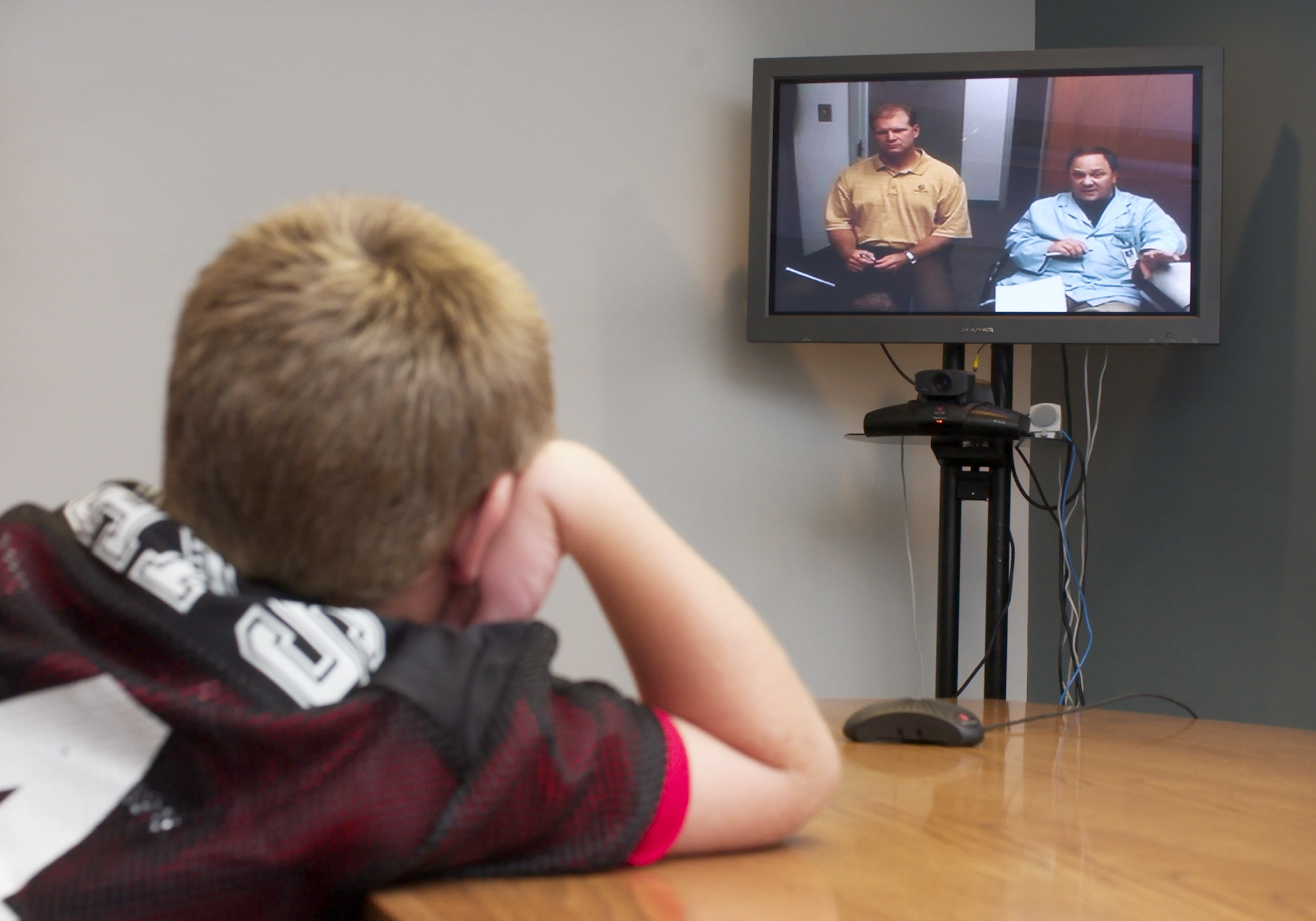 A student talks over video teleconferencing with his doctor and psychologist