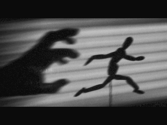 a shadow hand chasing a shadow figure