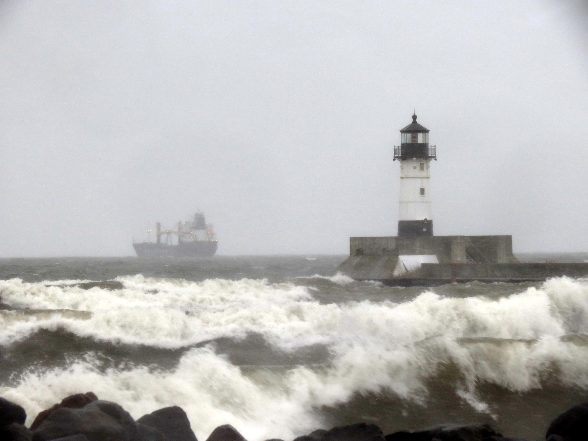 Waves crash against the north pier lighthouse at Duluth harbor's Canal Park