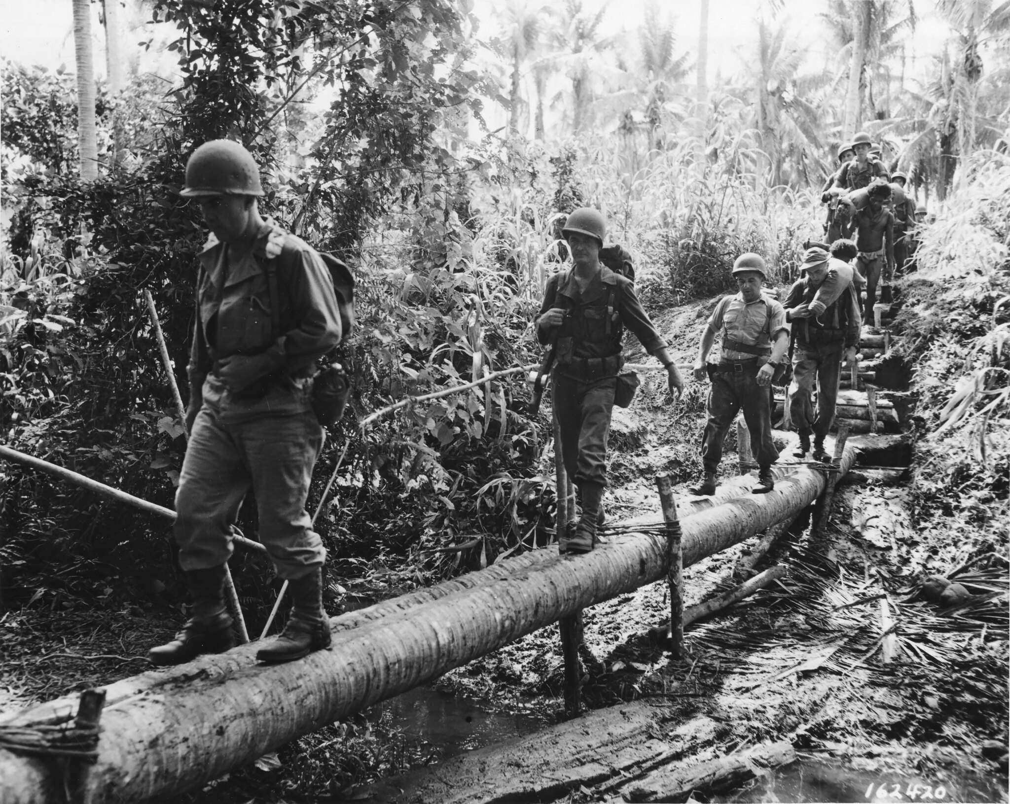 Wisconsin National Guard Soldiers, from the 32nd Division, cross a rudimentary log bridge in the South Pacific in 1942 during World War II.