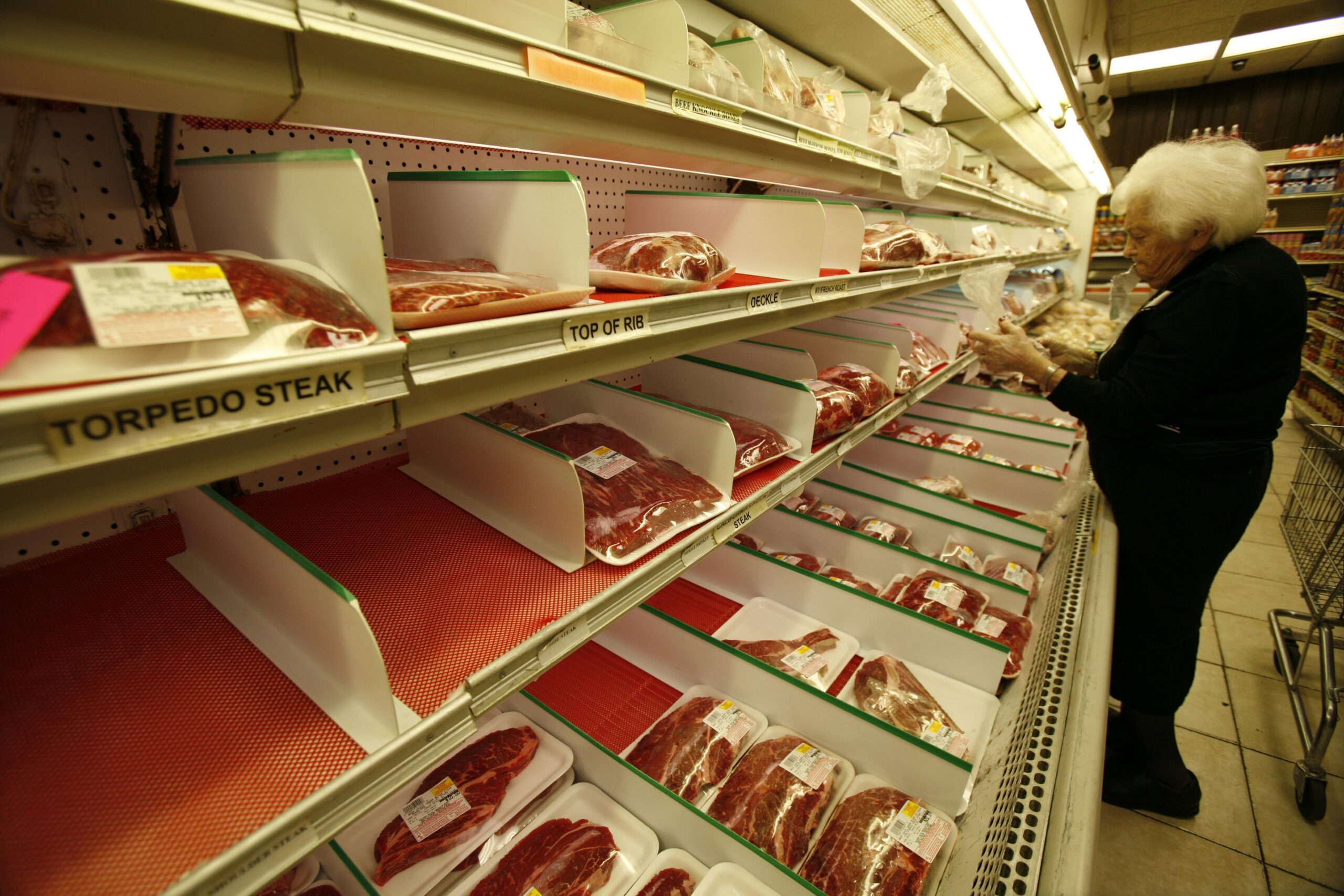 Person scanning meat counter at grocery store