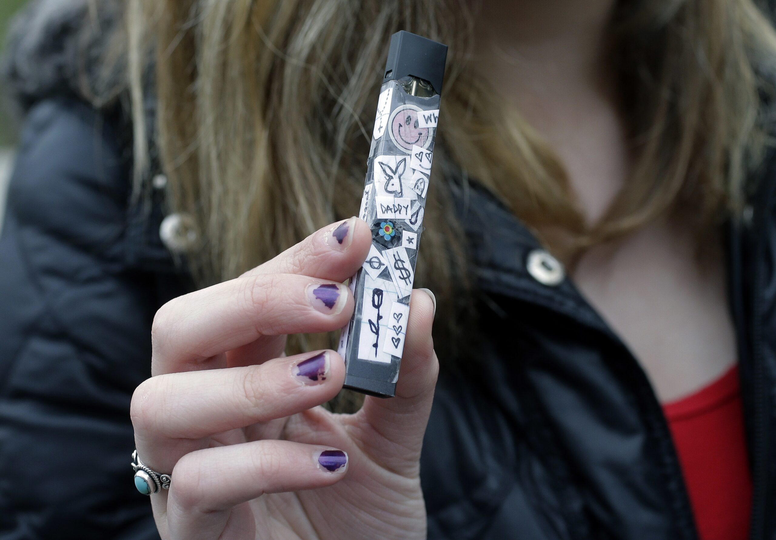 A high schooler holding her vaping device outside of her school in April 2018.