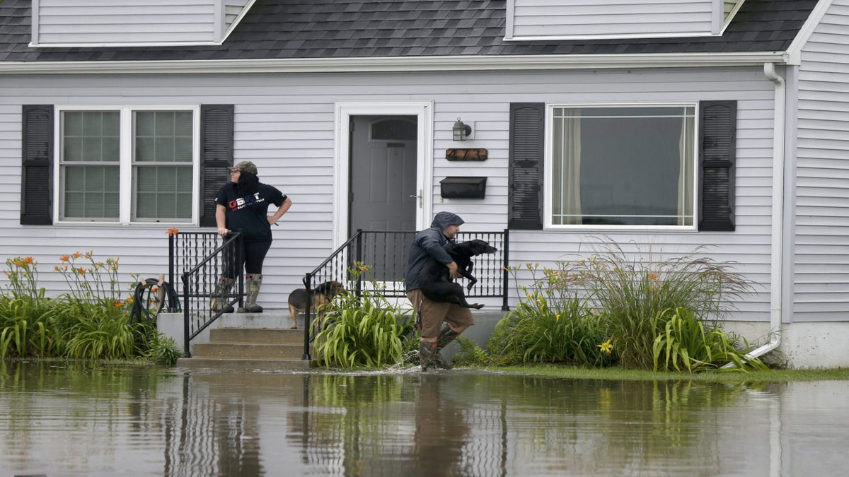 Jason O'Donnell carries his dog over the flood water