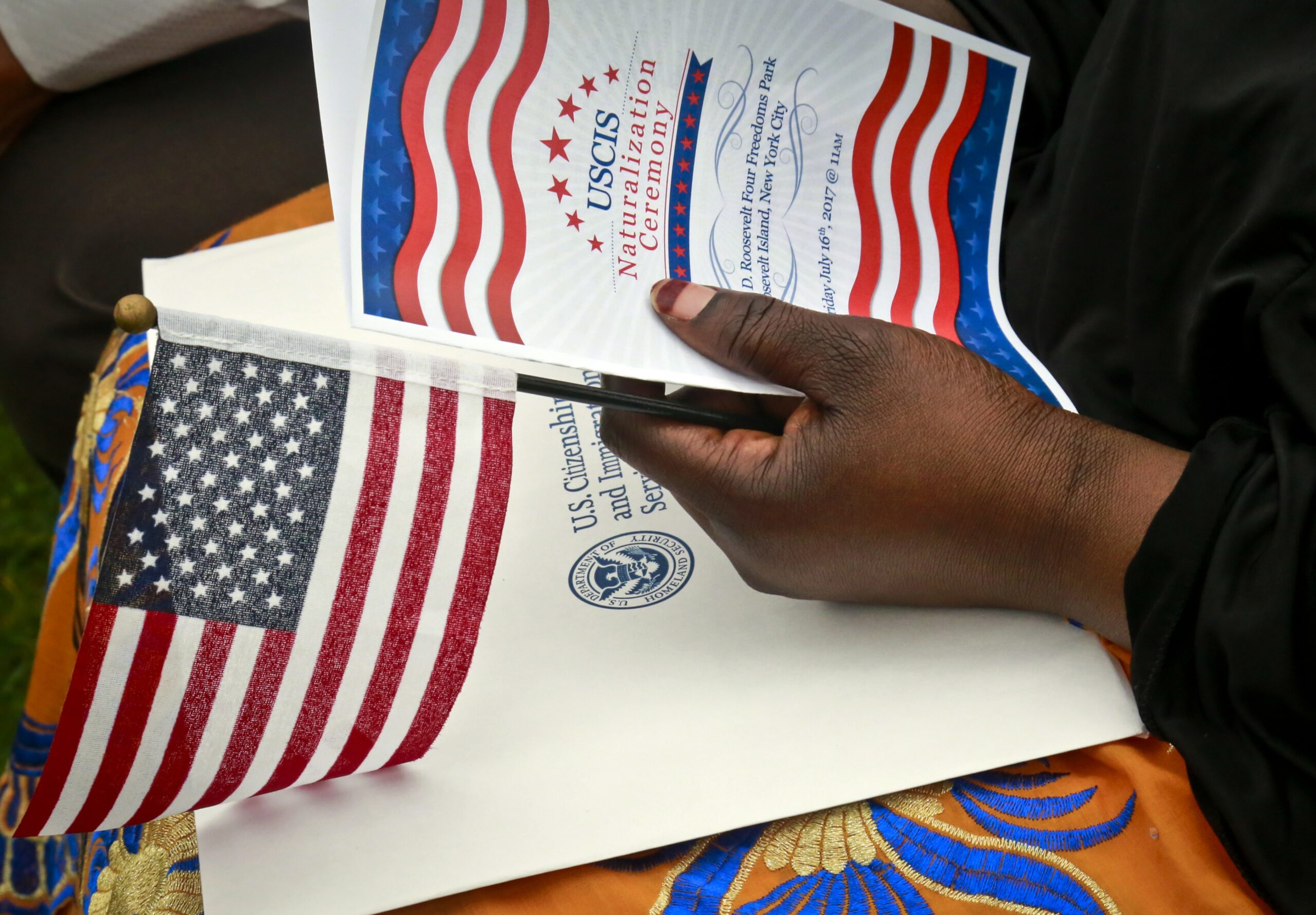 Fatoumata Jangana holds a program and flag during U.S. Citizen and Immigration Services ceremony