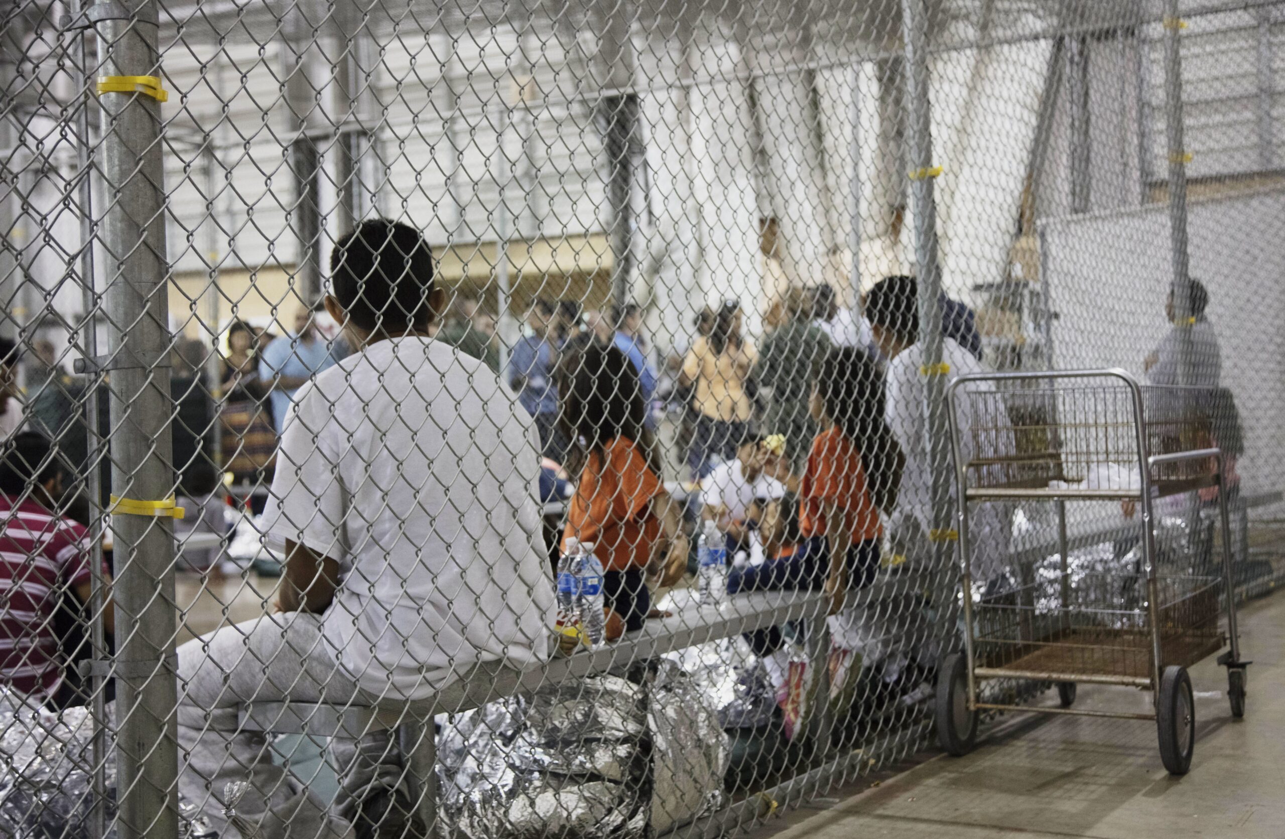 immigrants who've been taken into custody sit in one of the cages at a facility in McAllen, Texas