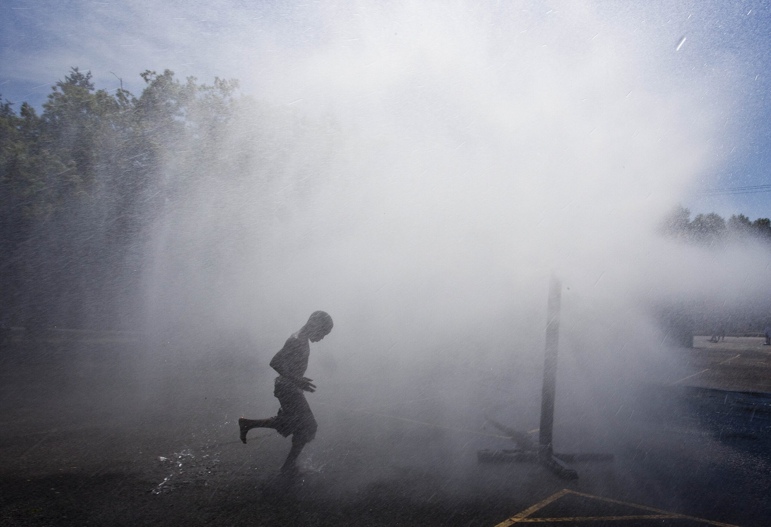 child playing in a sprinkler outside on a hot summer day