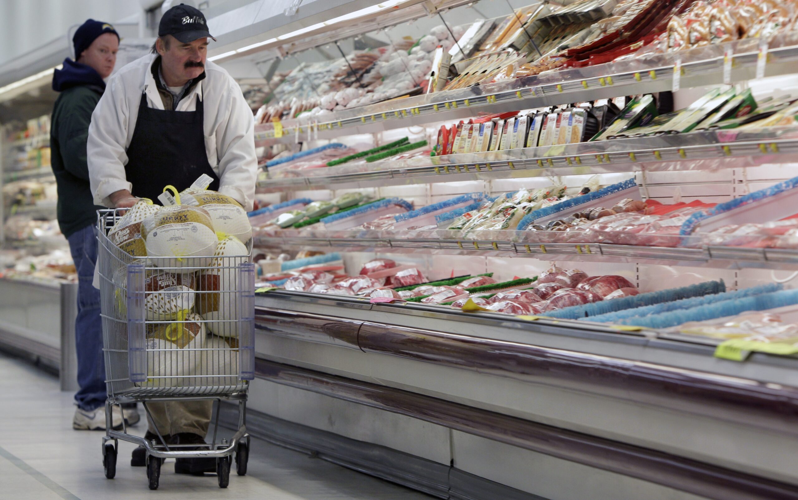 A meat manager, pushes a shopping cart full of turkeys for stocking