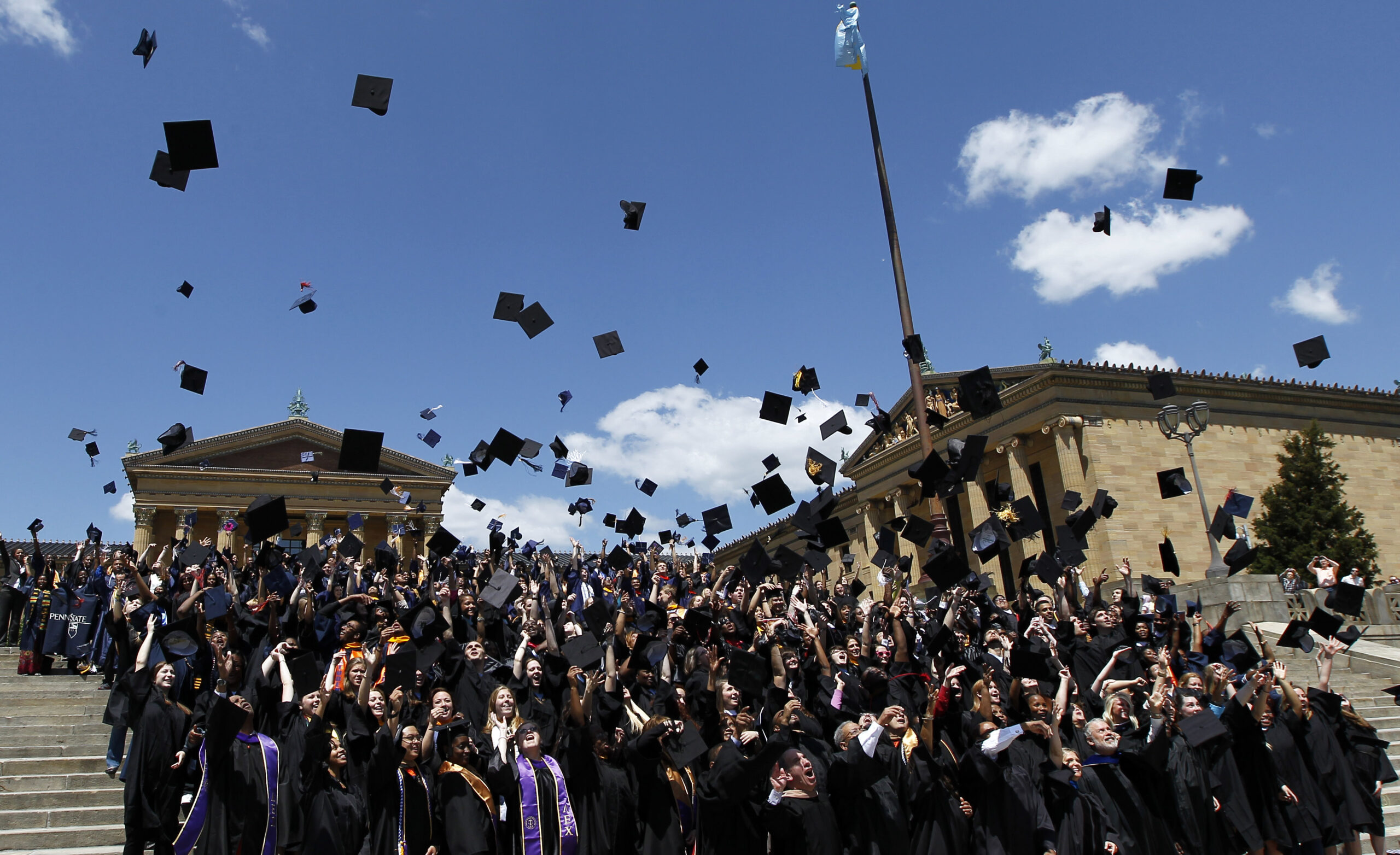 Graduating students throw mortarboards in the air
