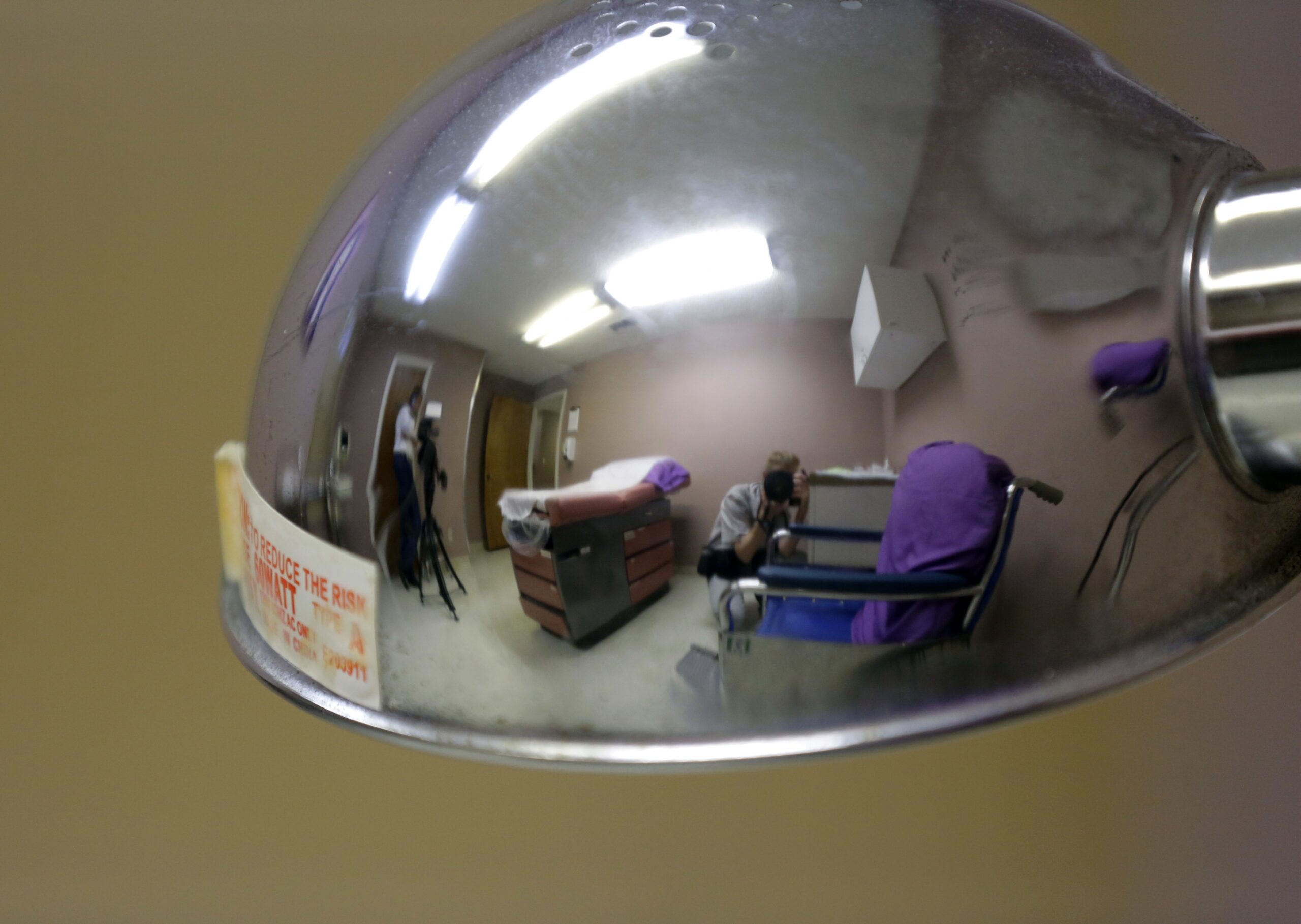 media are reflected in a lamp as they photograph a room formally used as an examination room for abortions