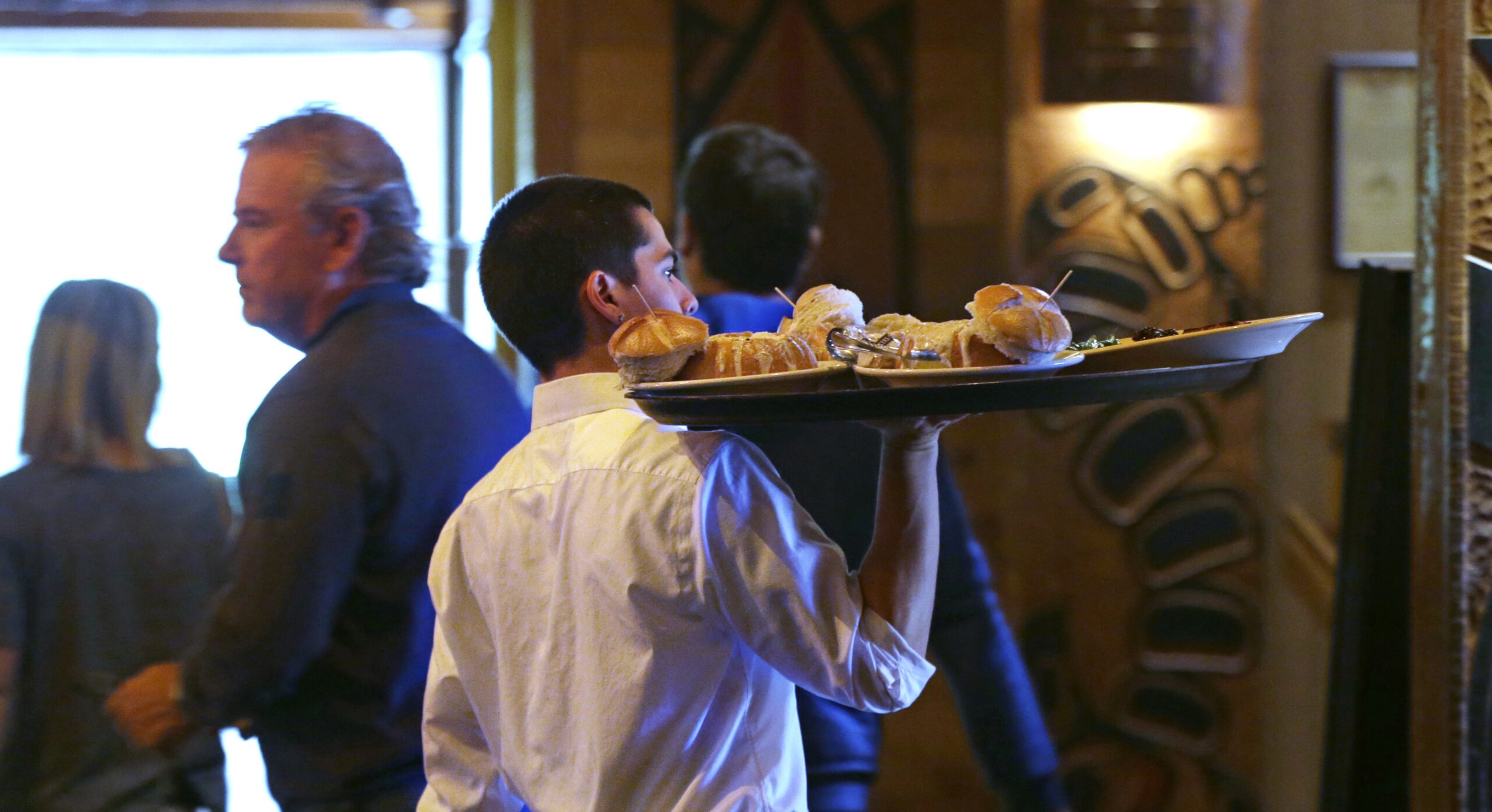 Server Zachary DeYoung carries a tray of food