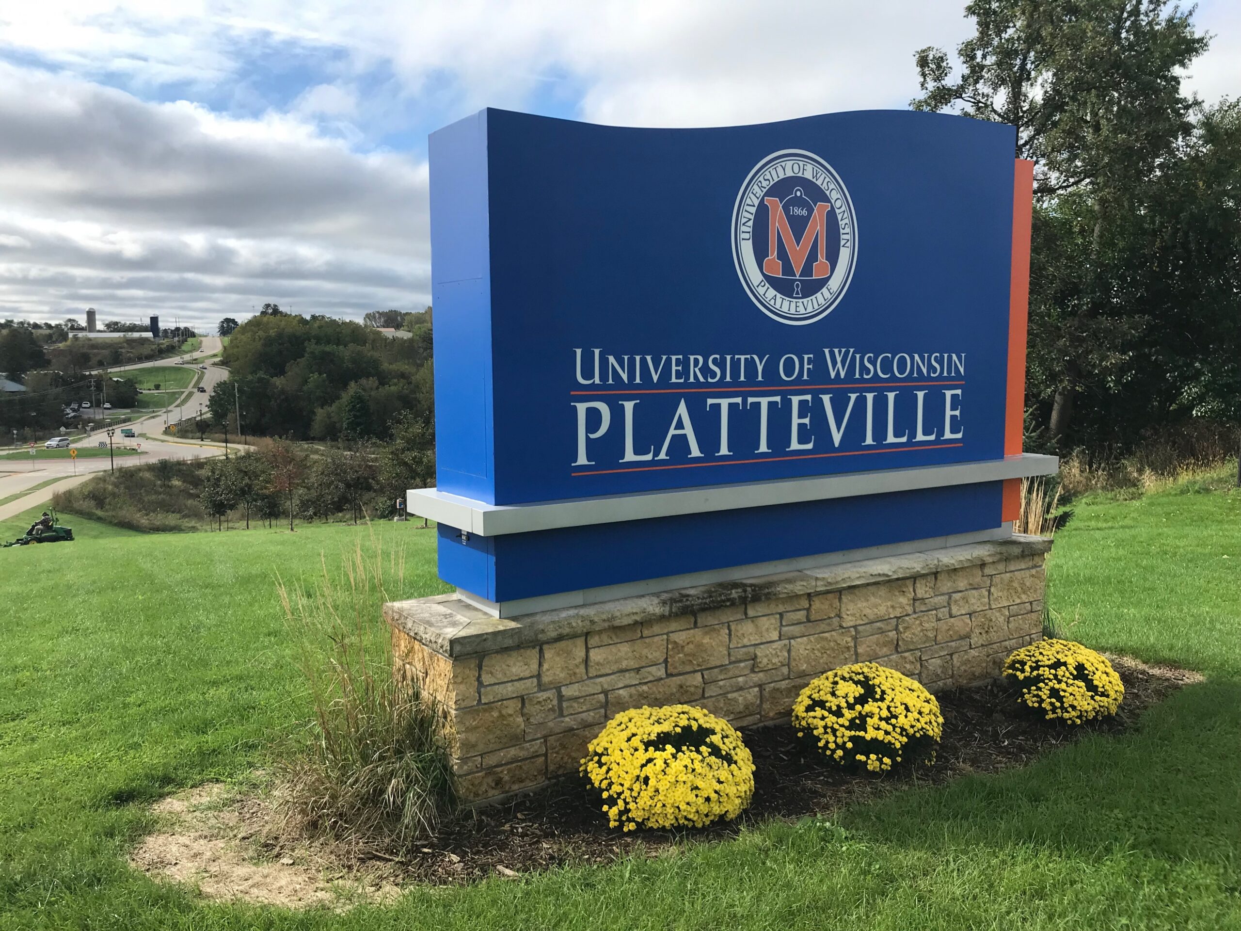 A blue sign reading "University of Wisconsin-Platteville" stands on the schools' campus.