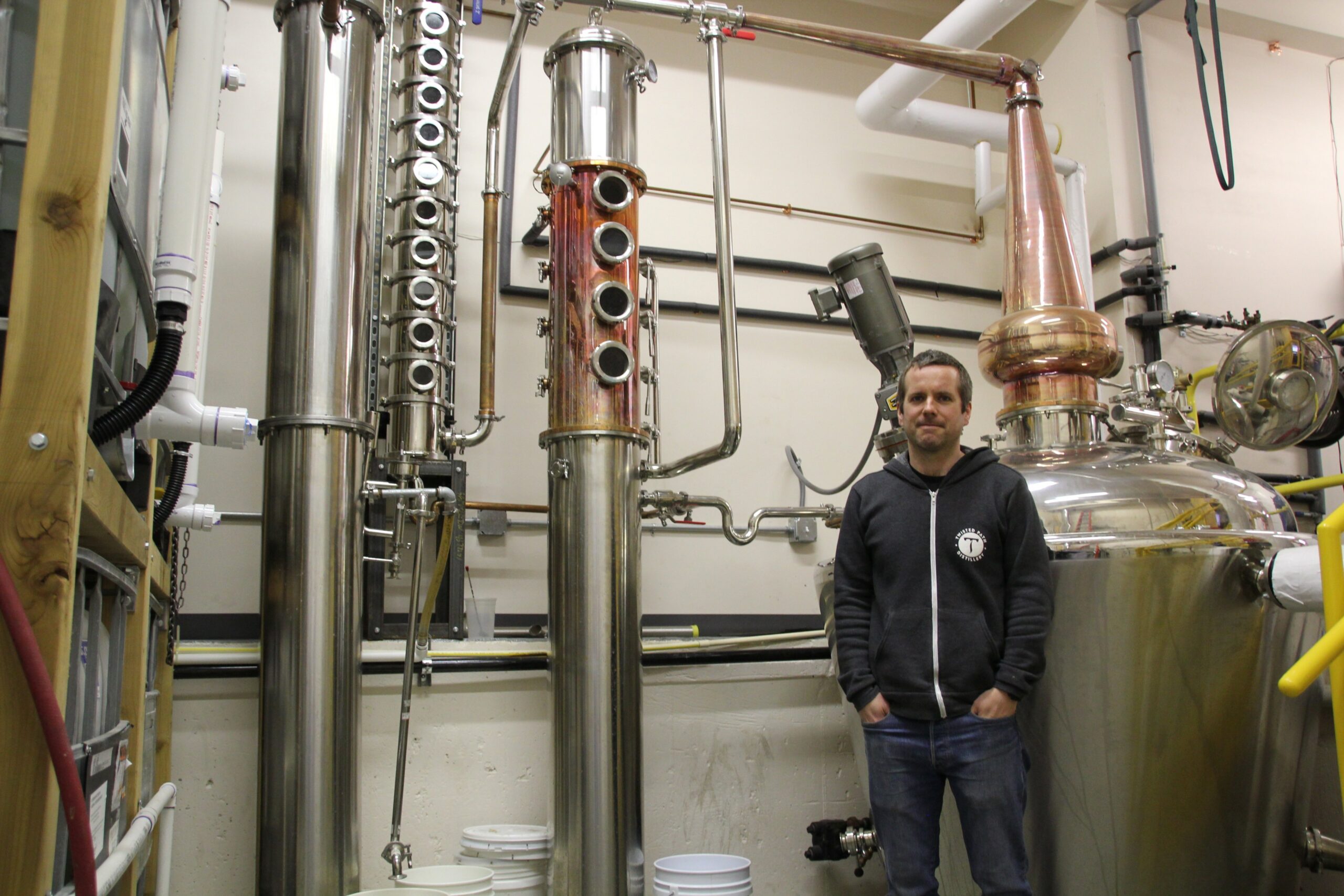 Brian Sammons stands in front of one of his stainless steel distillers.