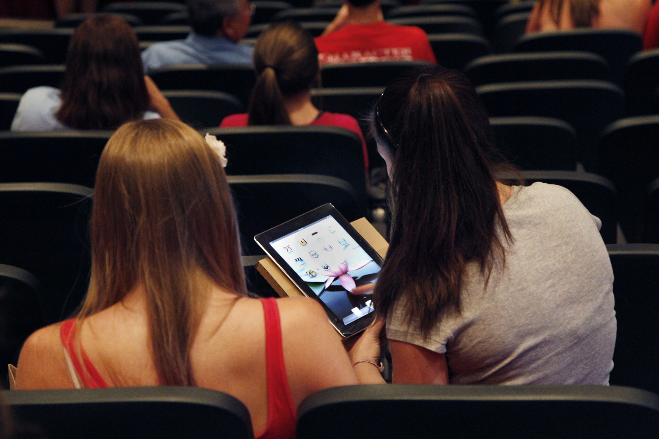 Girls on iPad in auditorium