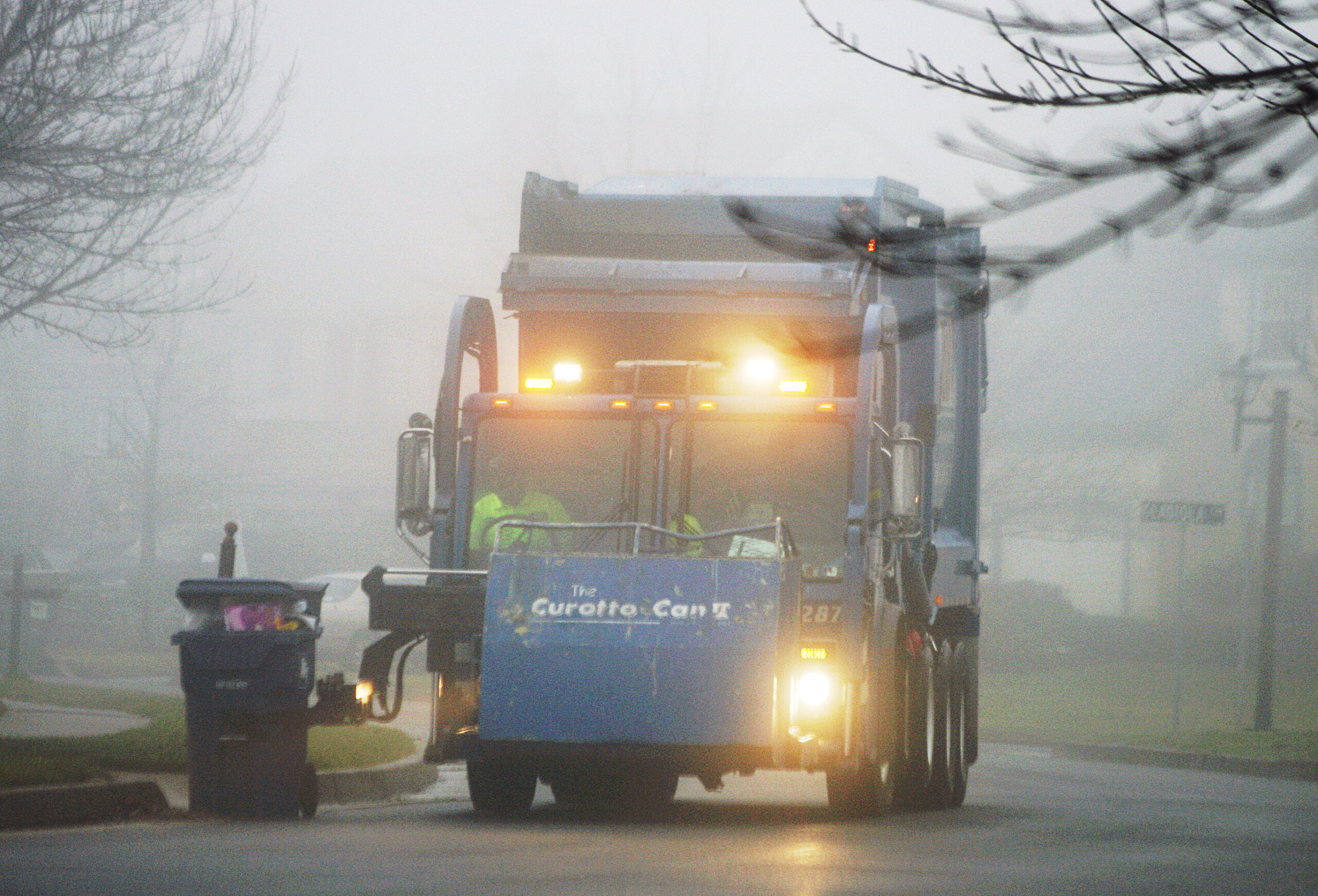 A truck collects trash on a foggy day after Christmas in Newtown, Pa.