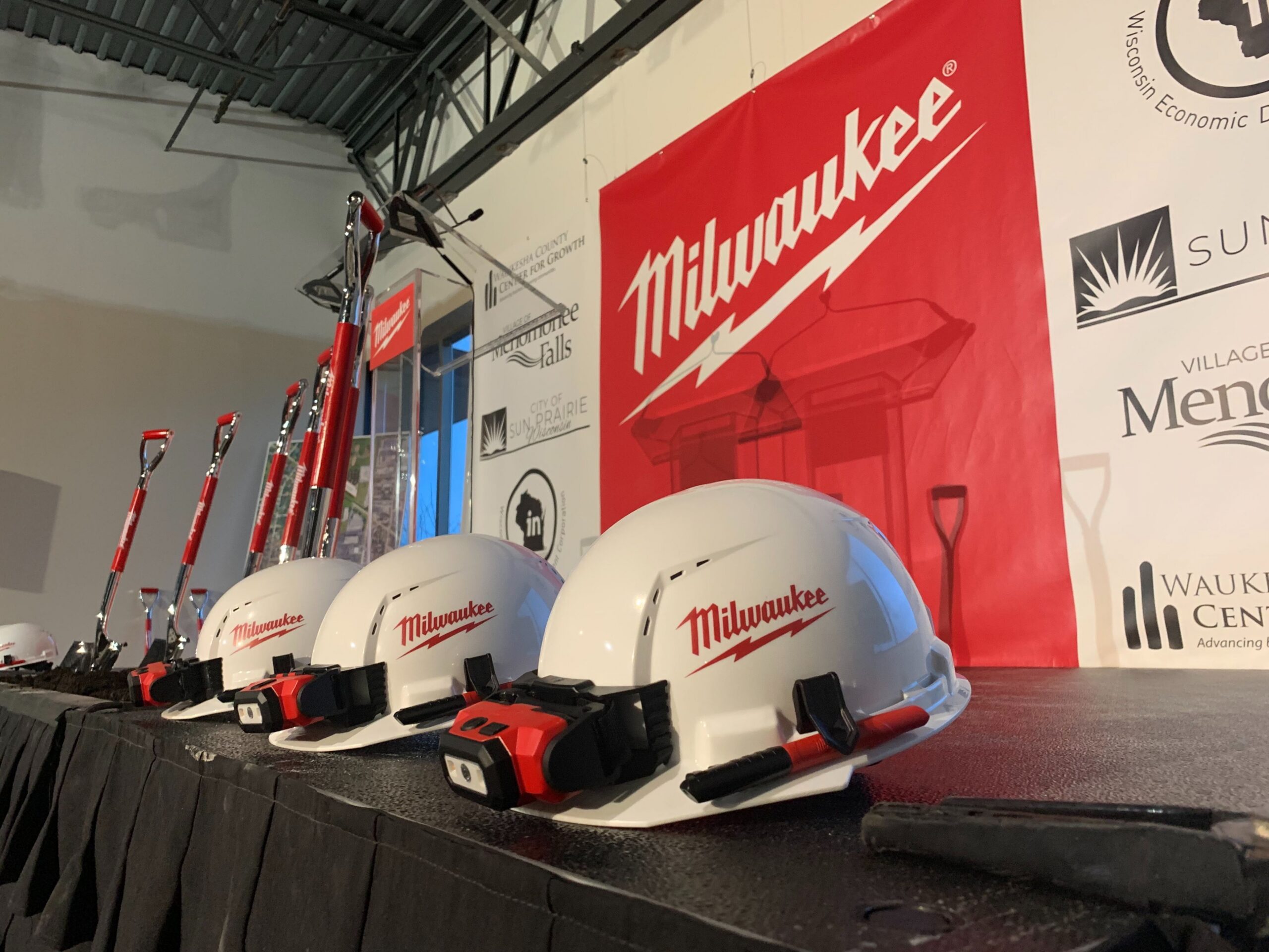 Hard hats and shovels are lined up at a groundbreaking event for Milwaukee Tool’s new facility in Menomonee Falls