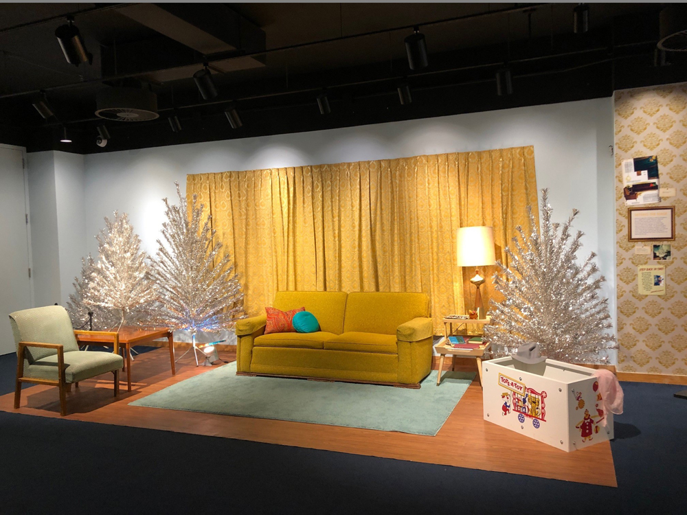 A 1960s-style living room is adorned with aluminum Christmas trees