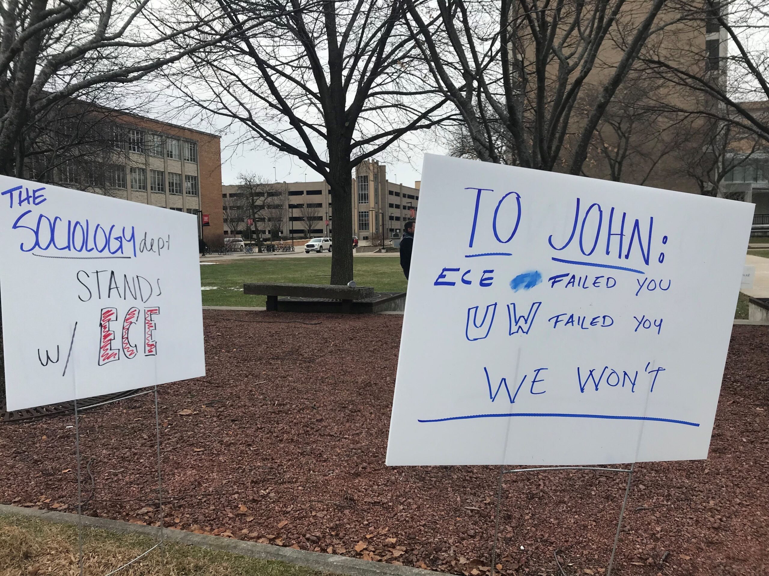 Two white signs stand in a patch of grass. One says 